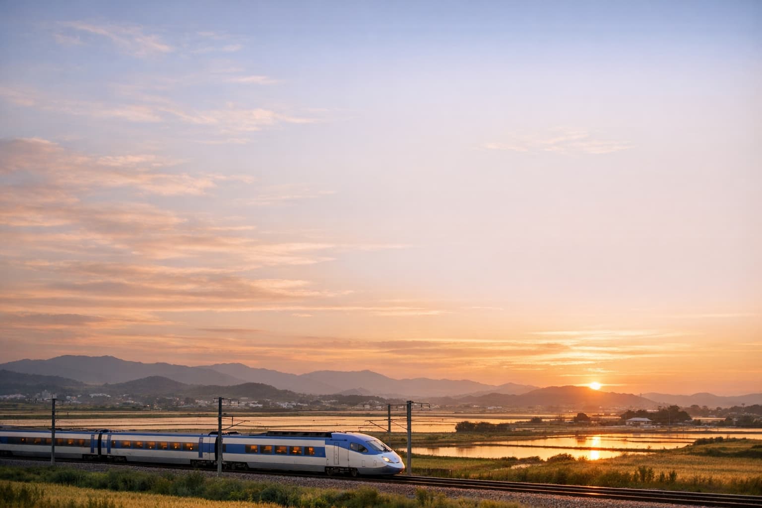 KTX train moving across a modern South Korea landscape at golden hour.